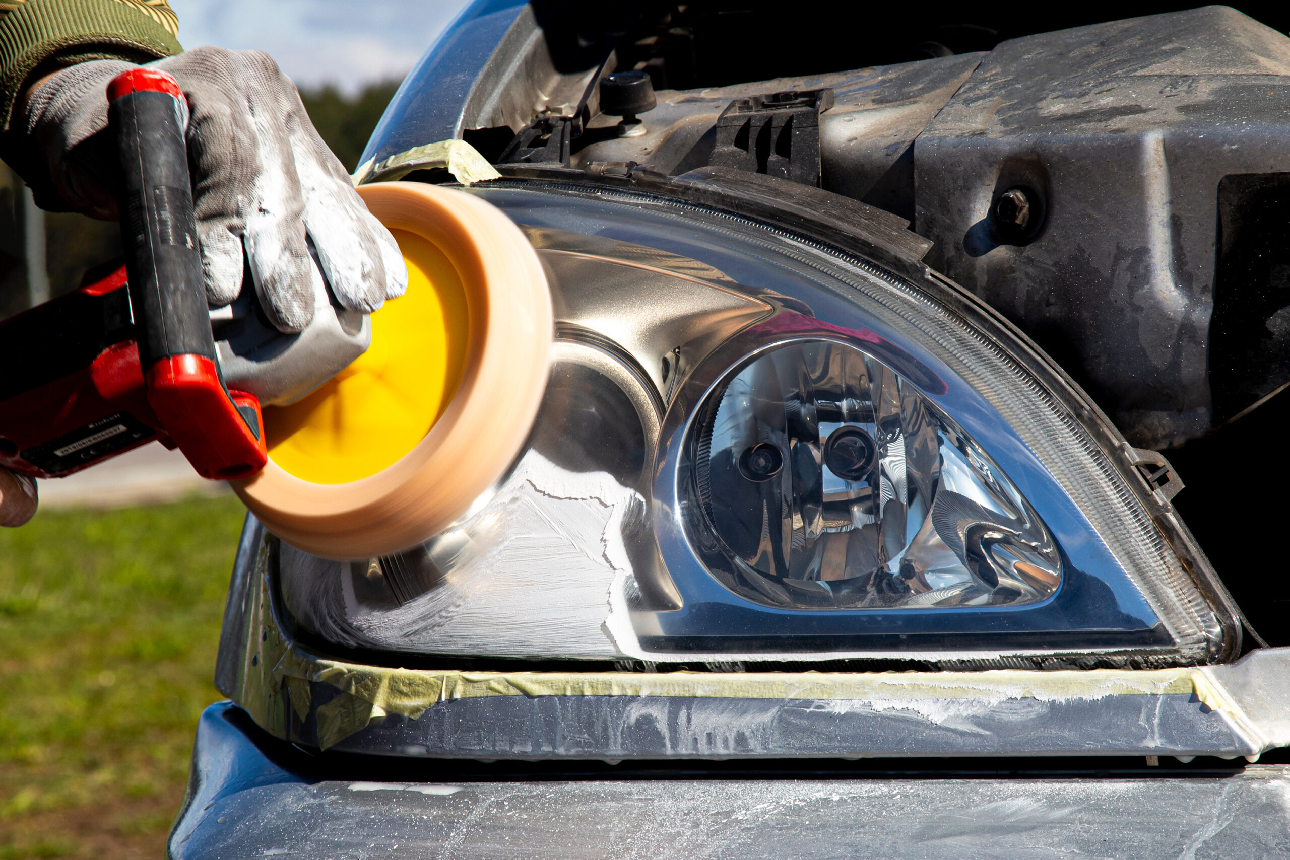 mechanical car headlight polishing, with yellow rag Mechanically polishing a car headlight using a yellow cloth during a restoration service